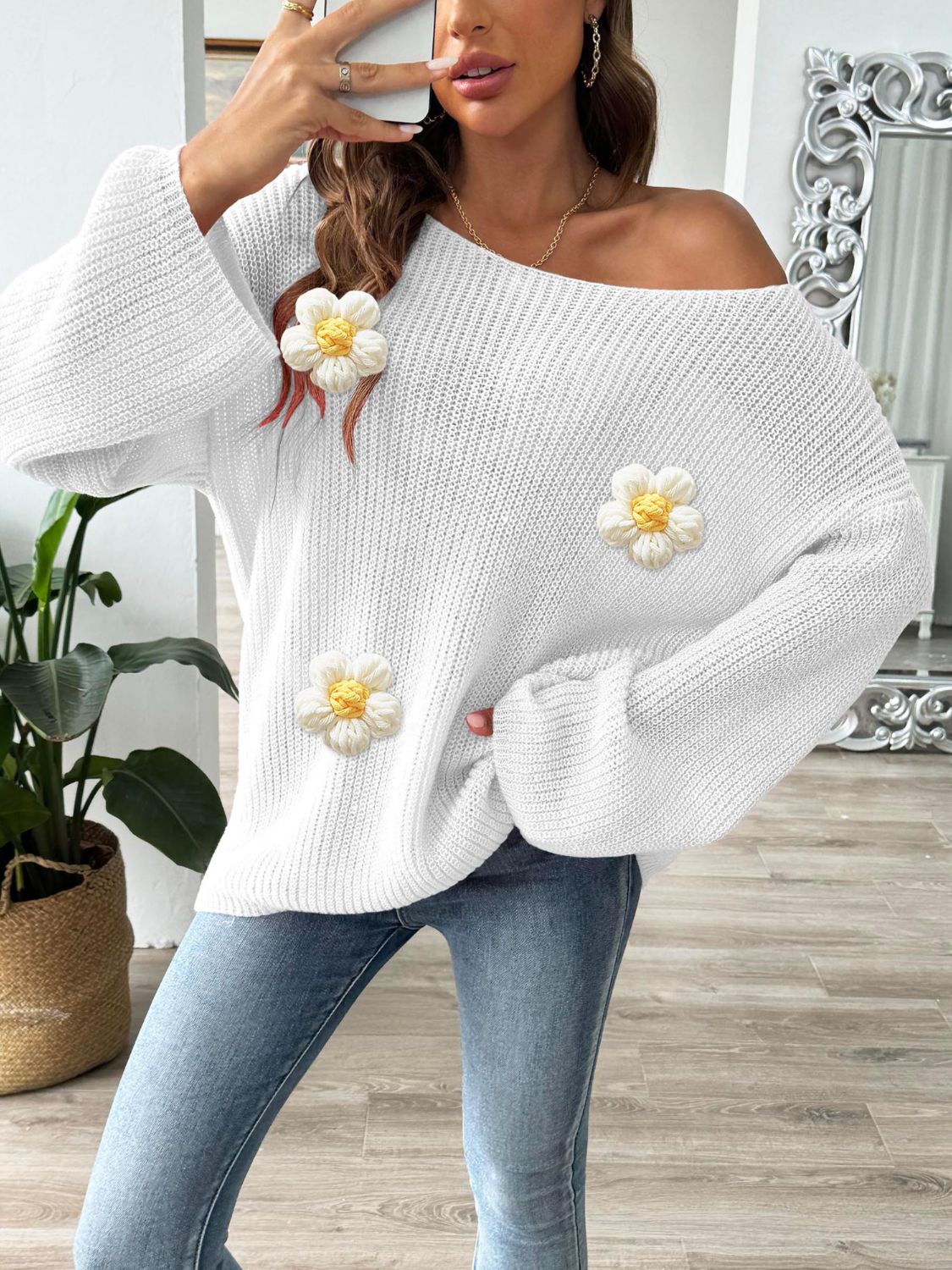 White slouchy knit sweater with floral appliqués and bell sleeves.