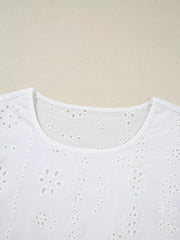 White cotton blouse with delicate eyelet embroidery and a ruffled neckline.
