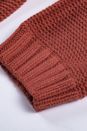 Cable knit sweater in rust acrylic with ribbed cuffs and neckline detail.