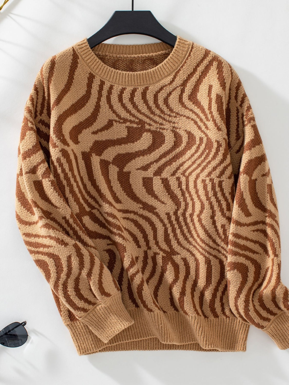 Camel wavy knit crewneck sweater with brown abstract pattern.