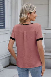 Dusty Pink blouse with black trim and short sleeves, featuring a textured fabric and back pleat detail.