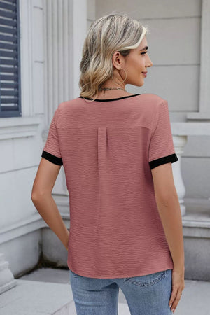 Dusty Pink blouse with black trim and short sleeves, featuring a textured fabric and back pleat detail.