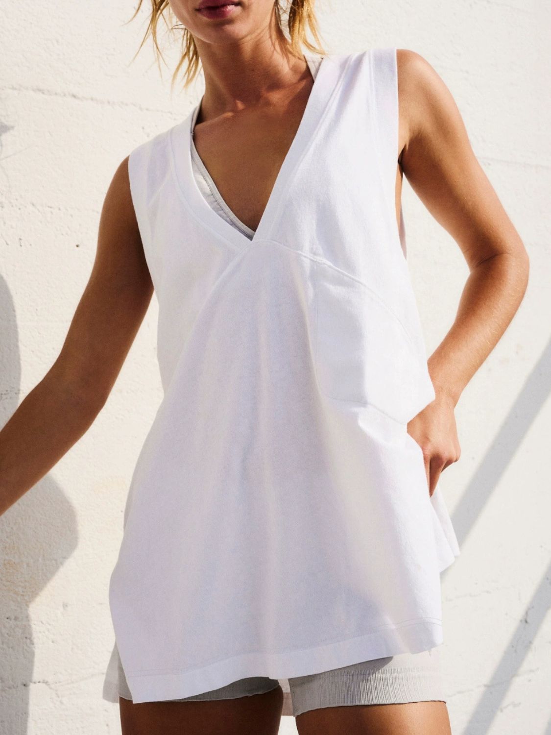 White wrap-front pocket tank top with a deep V-neck and sleeveless design.
