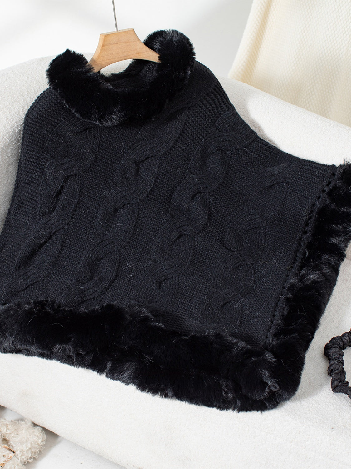 Black cable knit poncho with faux fur trim and collar detail.