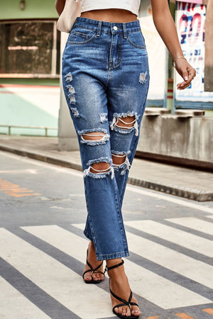 Distressed straight leg denim jeans in medium wash with ripped details and frayed hems.