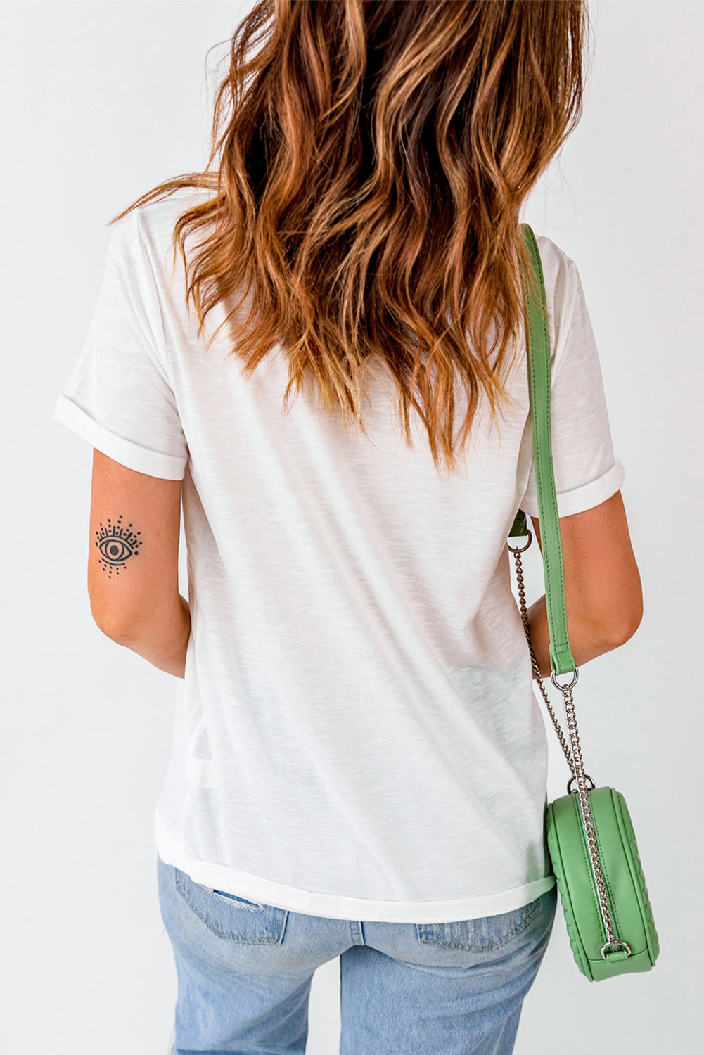 White casual tee with rolled sleeves and a black eye tattoo on the arm.