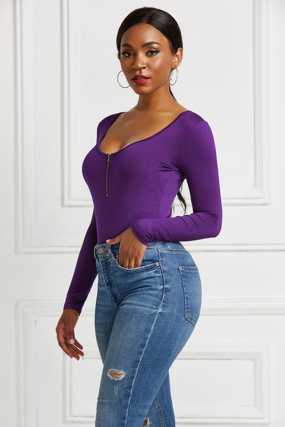 Purple long sleeve bodysuit with plunge neckline and zip front detail, styled with jeans.