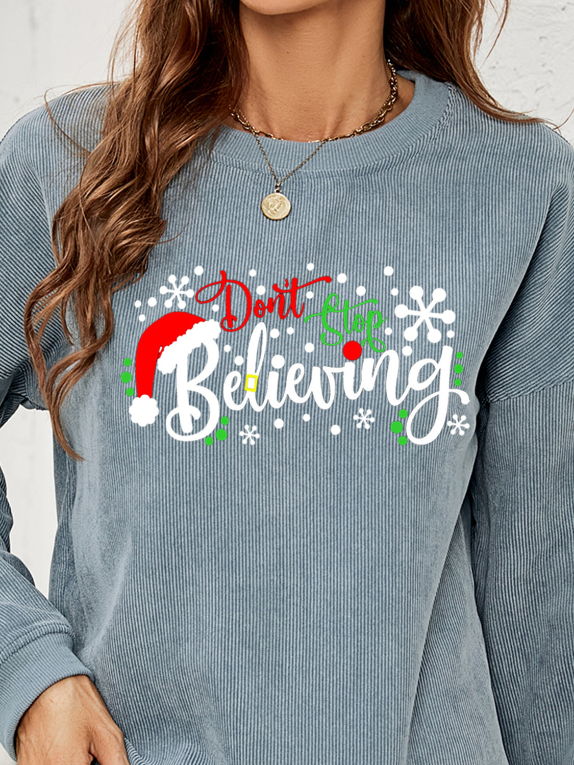 Misty Blue corduroy crewneck sweatshirt with a Christmas graphic that says "Don't Stop Believing".
