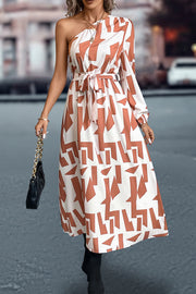 Asymmetric maxi dress with geometric print, belt, and one long sleeve.
