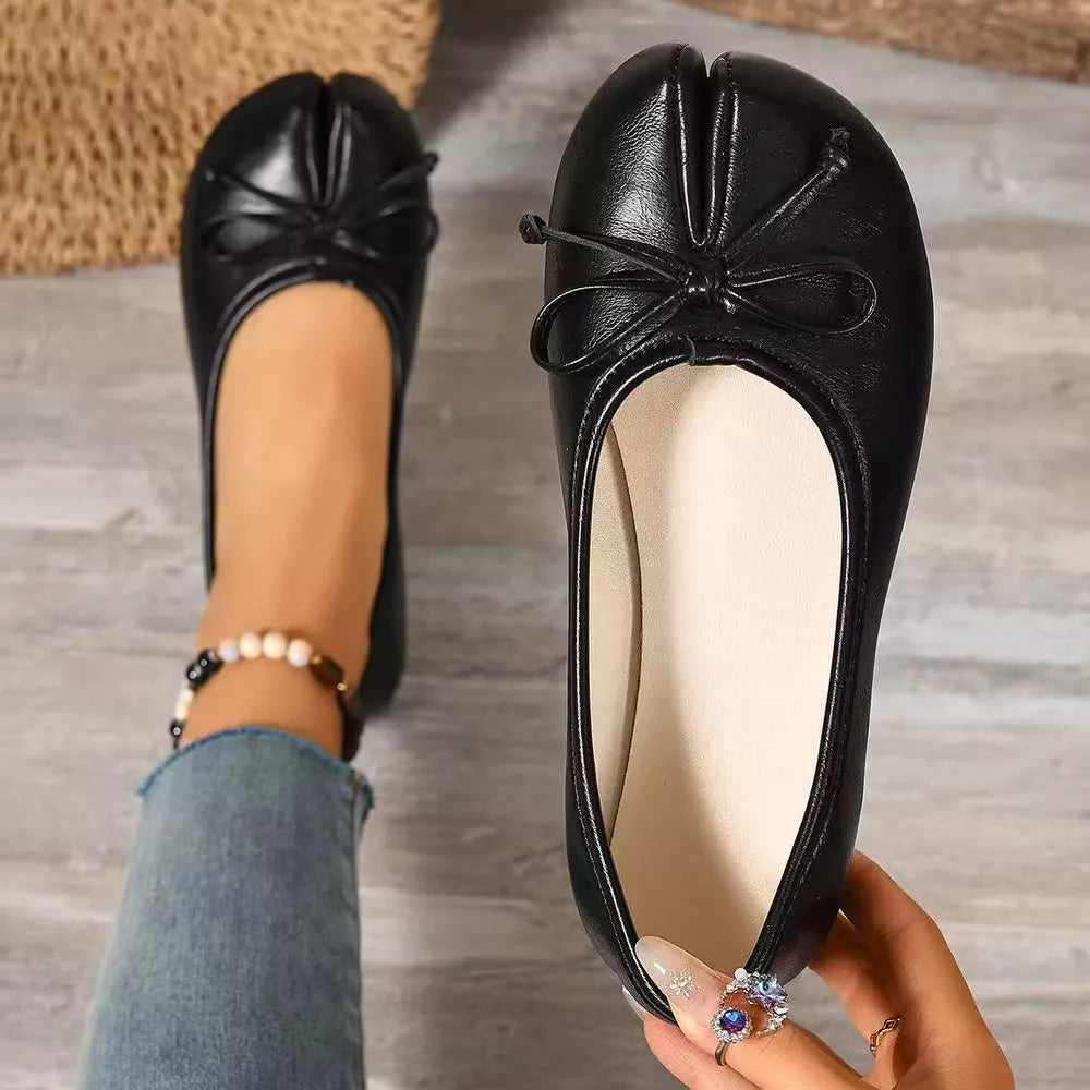 Black tabi slip-on flats with bow detail and split toe design.