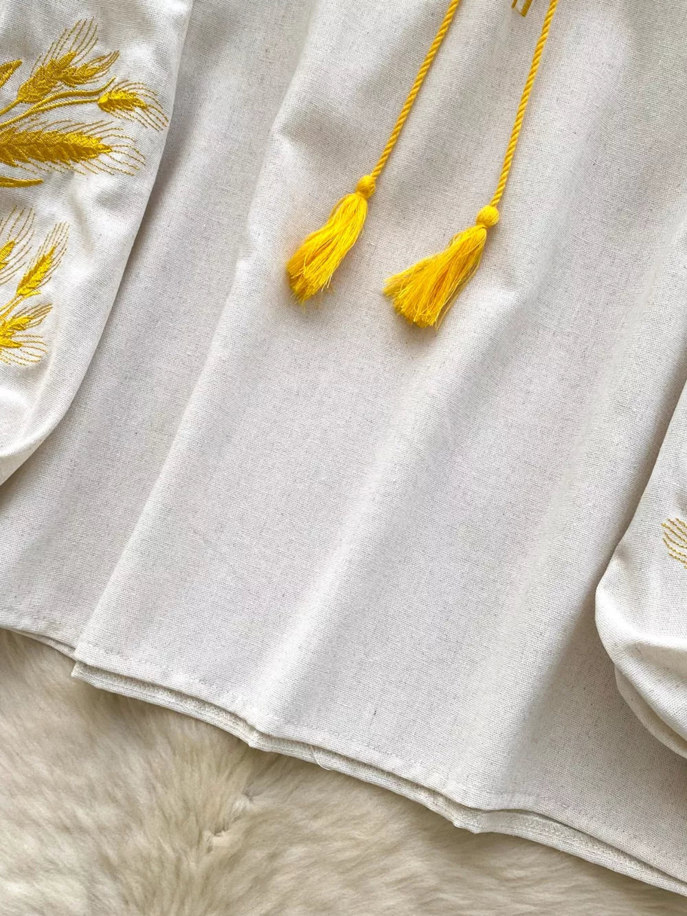 White embroidered tie-neck blouse with yellow tassels and wheat detail.