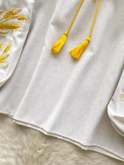 White embroidered tie-neck blouse with yellow tassels and wheat detail.