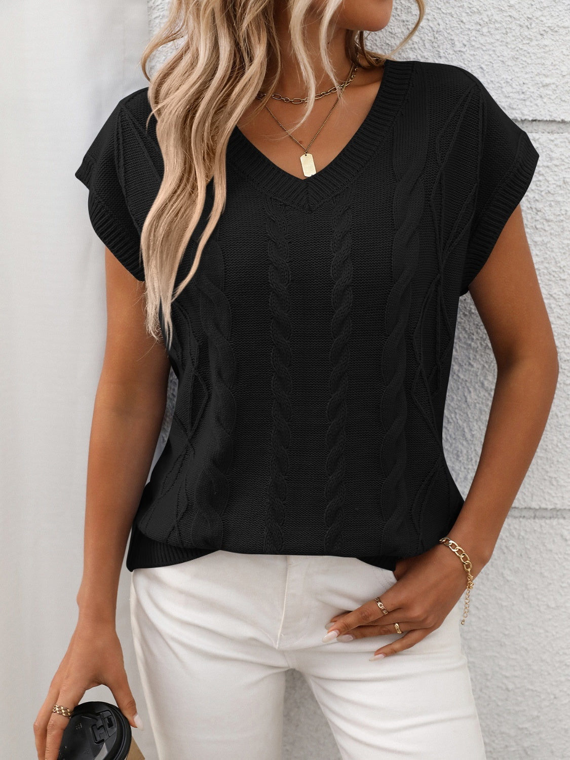 Black cable knit V-neck vest with short sleeves and textured knit pattern.