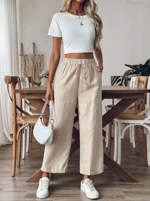 Chic high-waisted striped wide-leg pants in beige and white, featuring a relaxed fit and elastic waistband.