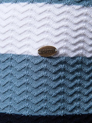 Chevron stripe knit polo shirt in white, blue, and dark navy with textured pattern and metal logo detail.