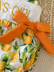 Baby one-piece with orange print, embroidered text, and orange bow detail.