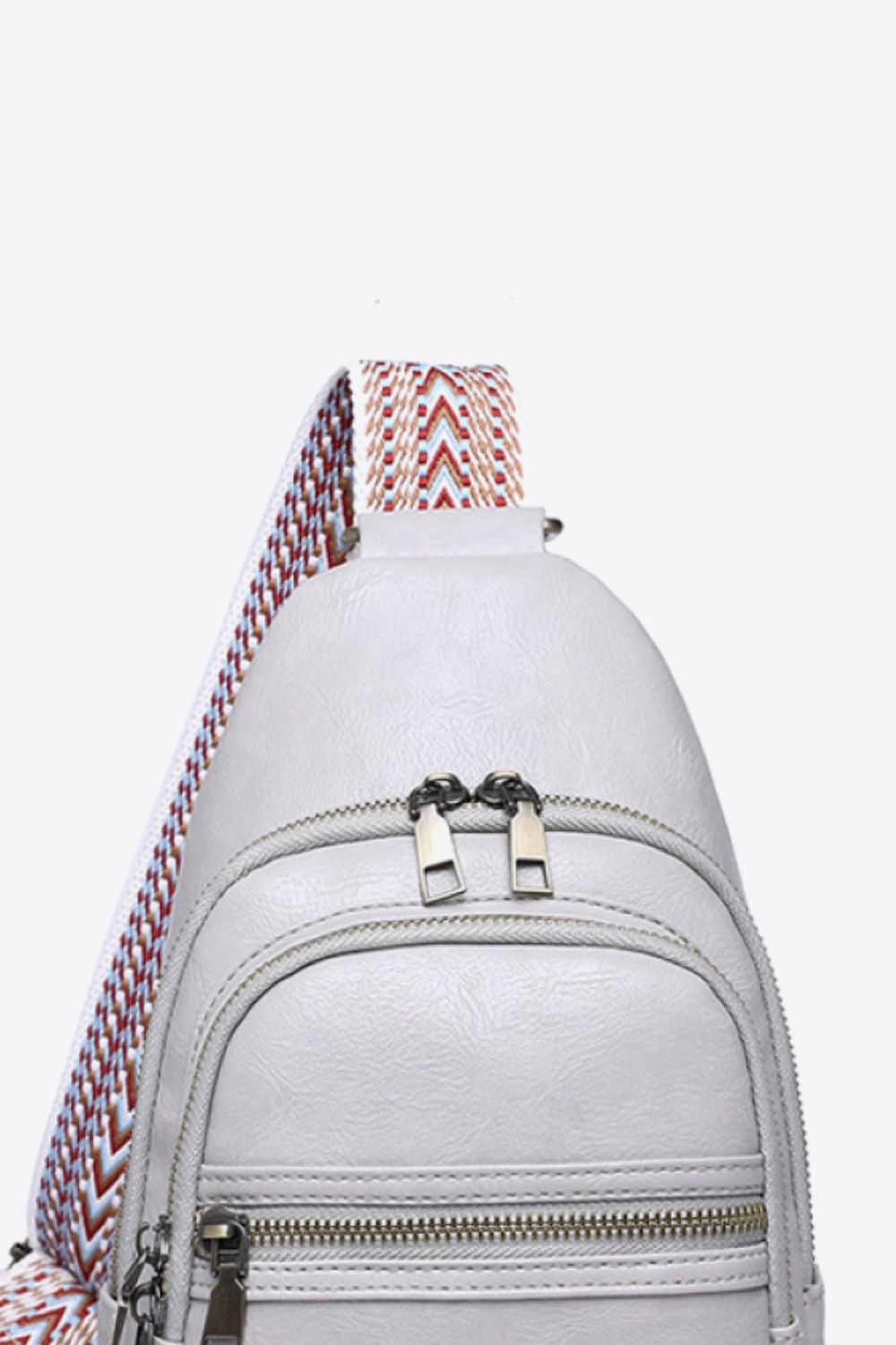 Geometric strap sling bag in Mid Gray with chevron strap detail and double zipper closure.