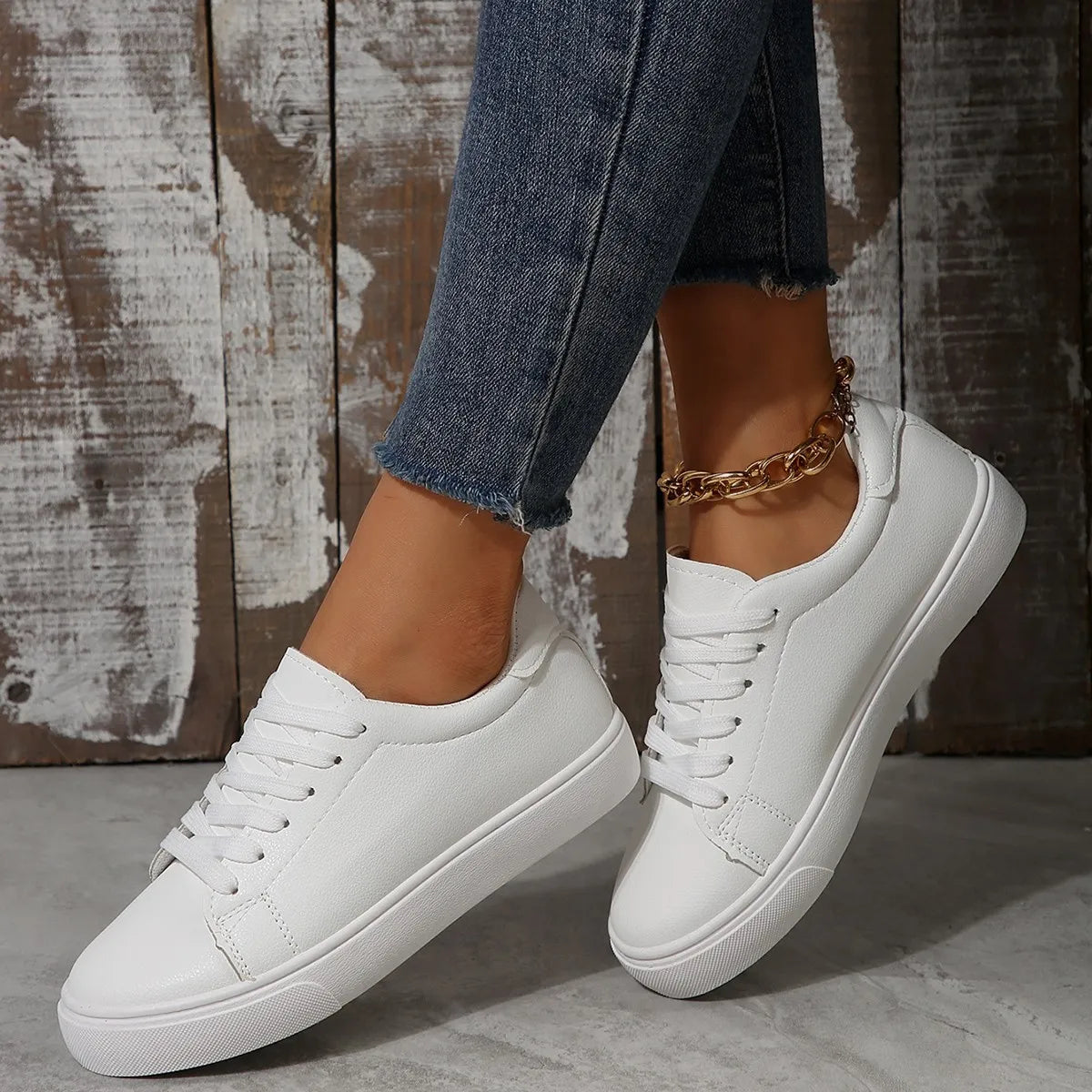 White leather-look platform sneakers with lace-up closure and gold chain ankle bracelet.