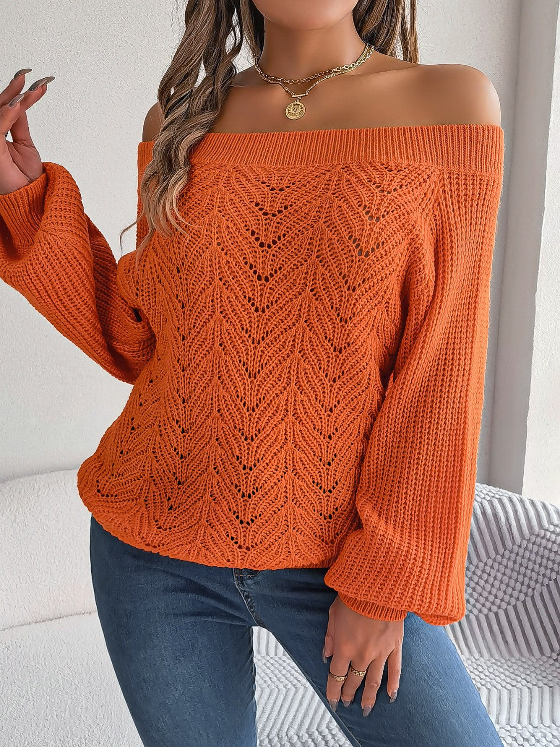 Pumpkin open-knit off-shoulder sweater with voluminous sleeves and intricate leaf pattern.