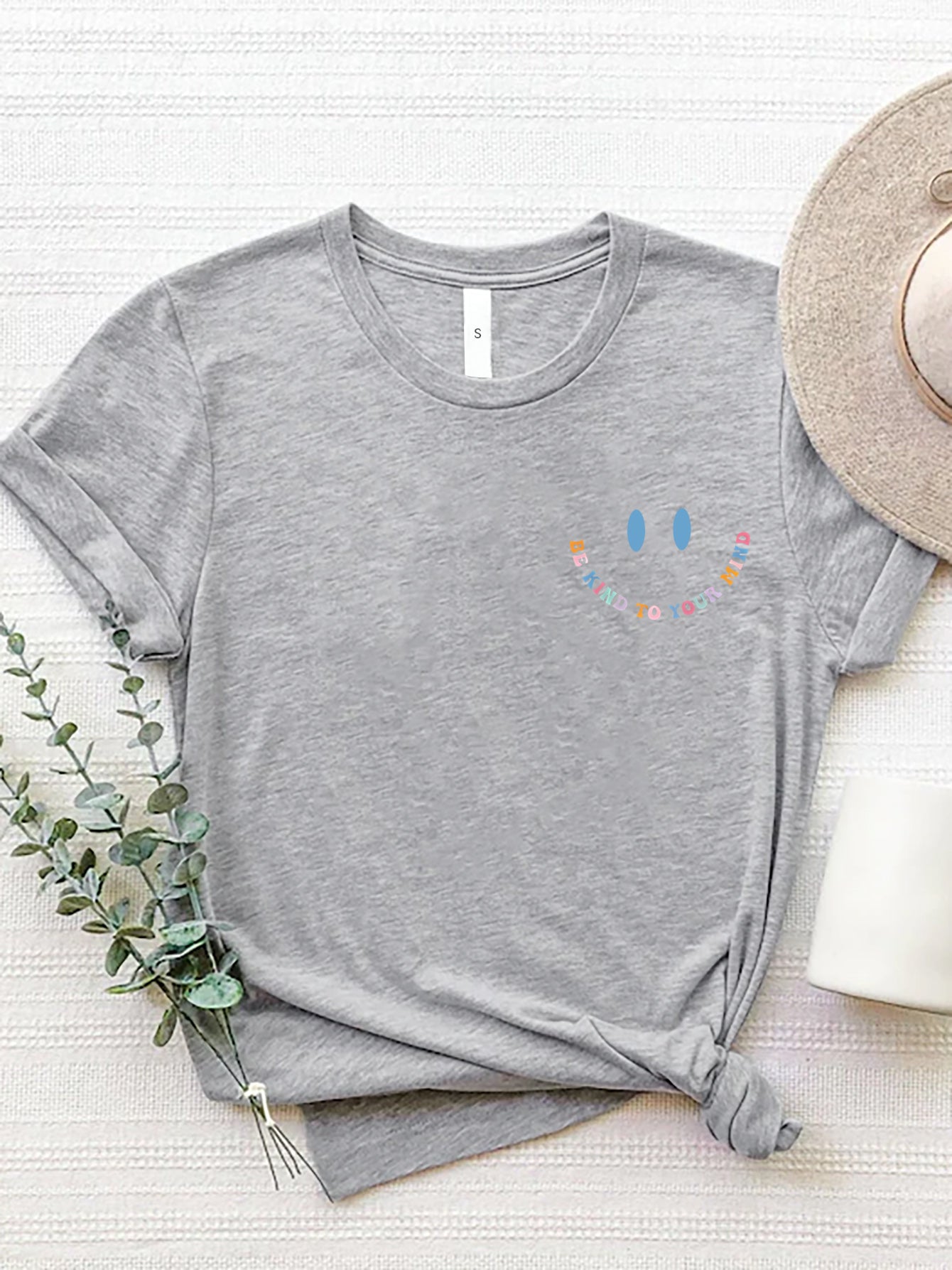 Gray crew neck t-shirt with a colorful smiley face graphic that says Be Kind To Your Mind