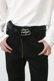 Black denim trousers with flared seam detail and silver buckle, styled casually.