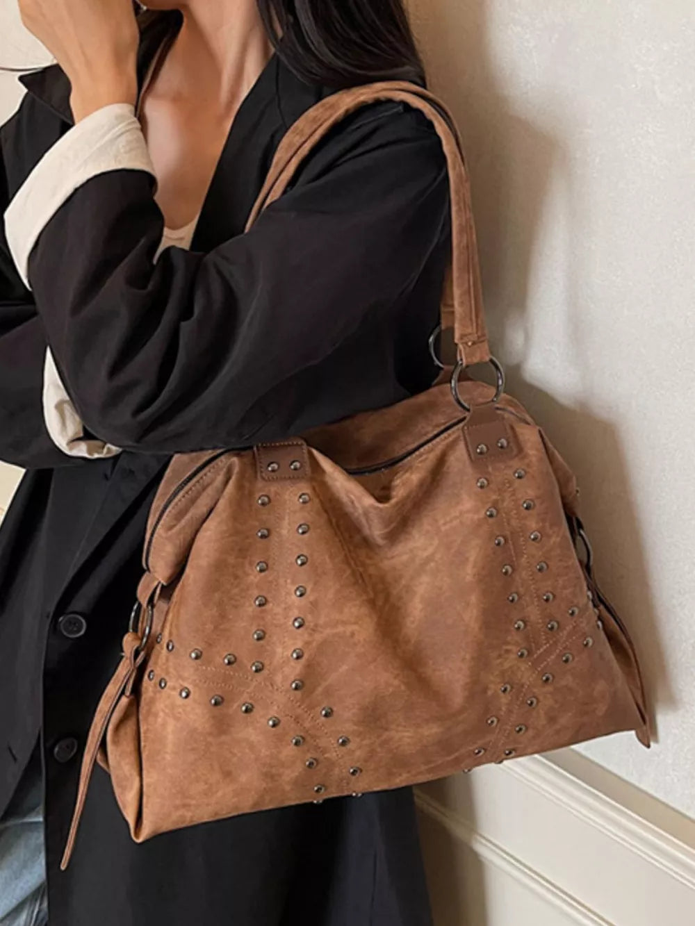 Brown distressed studded trapezoid handbag with vintage detailing.