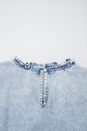Light wash denim top with ruffled neckline and pearl button back closure
