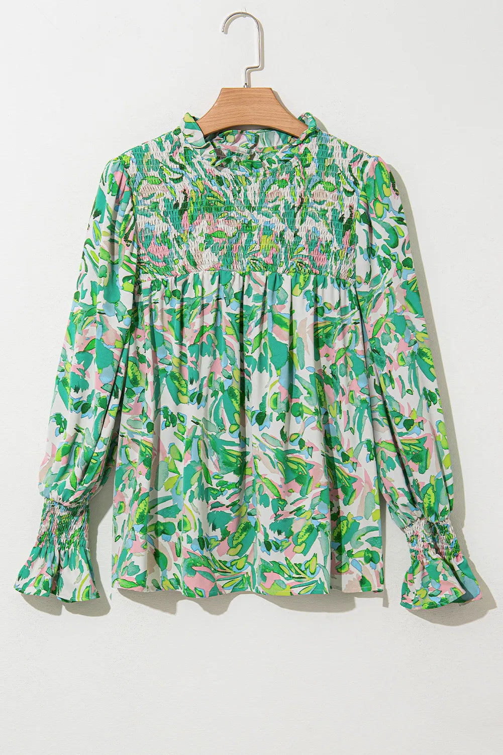 Green floral print blouse with smocked yoke, ruffled collar, and voluminous sleeves.