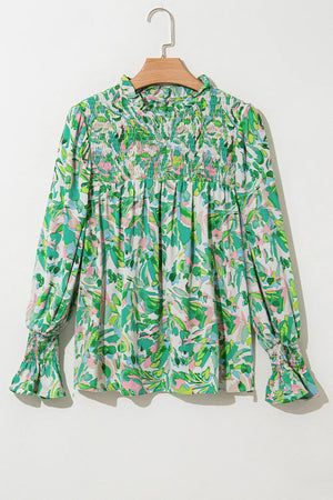 Green floral print blouse with smocked yoke, ruffled collar, and voluminous sleeves.