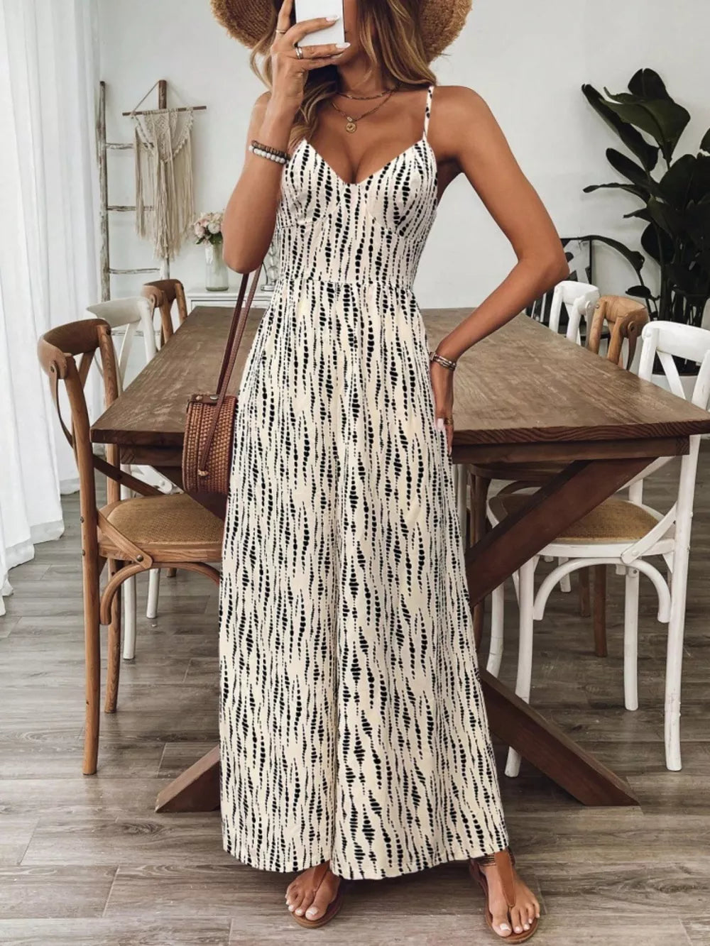 Backless wide-leg jumpsuit in cream with black abstract print, spaghetti straps, and V-neck.