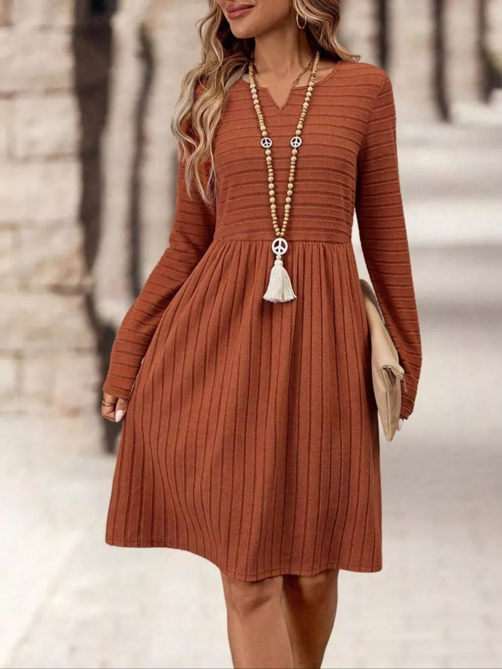 Ribbed knit A-line dress with long sleeves in rust, V-neck, and a gathered skirt.