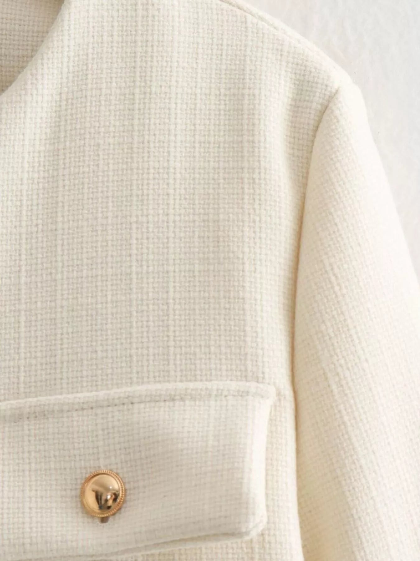 White tweed cropped jacket with gold button detail and pocket.