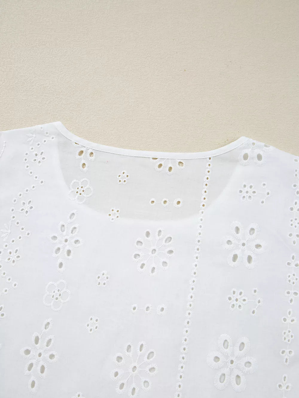 White cotton blouse with delicate eyelet embroidery and floral details.