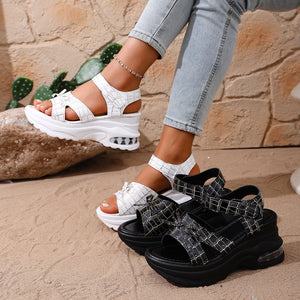 Textured open-toe wedge sandals in white and black with adjustable straps and air cushioning.