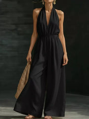 Black halter jumpsuit with deep V-neck, elastic waist, and wide-leg pants.
