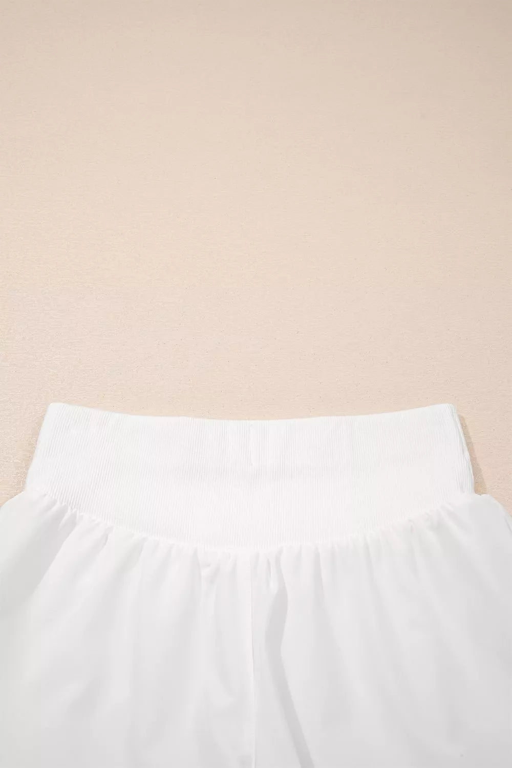 White ribbed-waist high rise relaxed shorts with a gathered fabric detail.