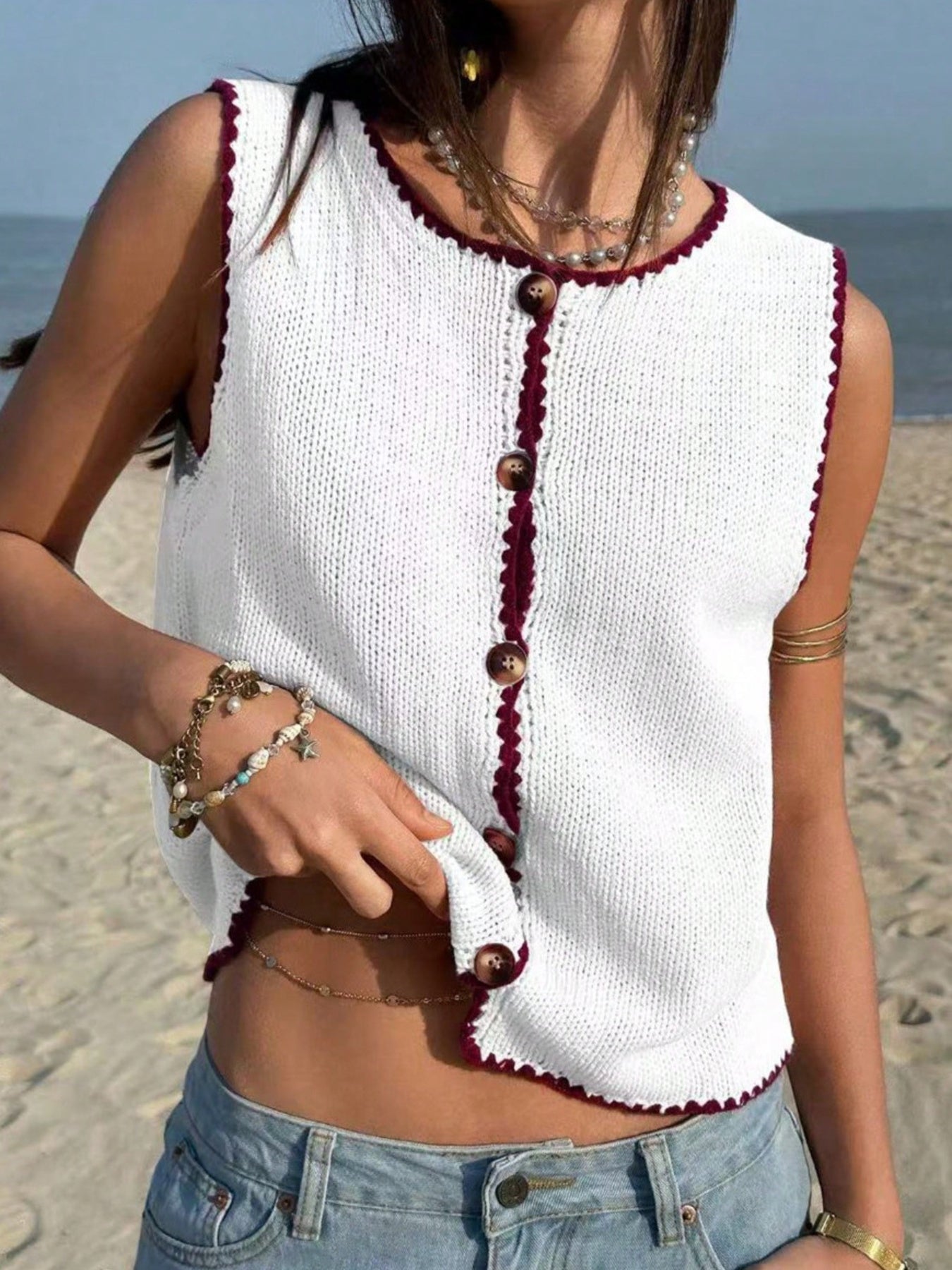 White button-down knit sweater vest with burgundy trim and buttons.