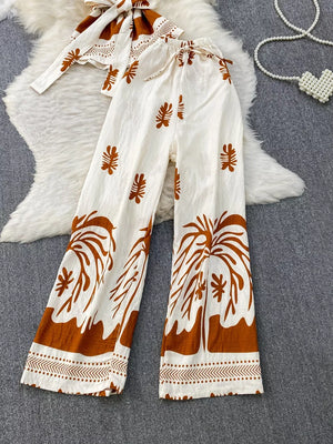 Tropical print two-piece set with belted detail in white and brown polyester, featuring wide-leg pants and a tie-front top.