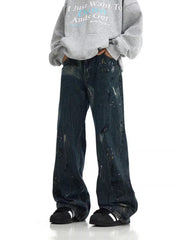 Distressed dark blue cotton wide-leg jeans with paint splatters and rips.
