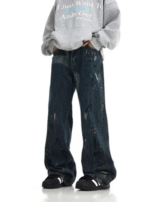 Distressed dark blue cotton wide-leg jeans with paint splatters and rips.