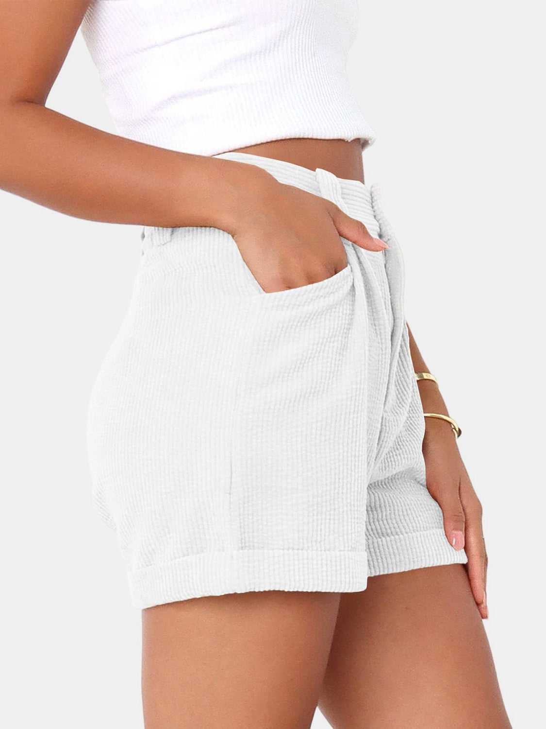 White corduroy pleated high-waist shorts with cuffed hem and pockets.