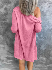 Watermelon pink cotton cardigan with long sleeves and pockets, styled off the shoulder.