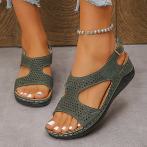 Green cutout wedge sandals with adjustable ankle strap and perforated detail.