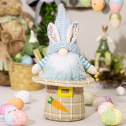 Easter gnome with blue bunny hat and carrot decor, white beard, blue striped sleeves, on plaid base.