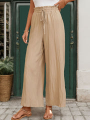 Tan textured wide-leg drawstring trousers with a crinkled fabric detail.