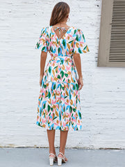 Botanical print midi dress with tie back, puff sleeves, and tiered skirt.