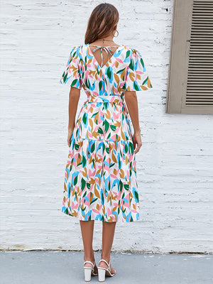 Botanical print midi dress with tie back, puff sleeves, and tiered skirt.