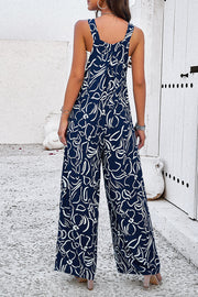 Dark blue wide leg jumpsuit with abstract white floral print and square neckline.