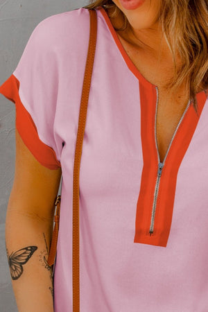 Blush pink short sleeve blouse with orange colorblock detail and zip-front neckline.