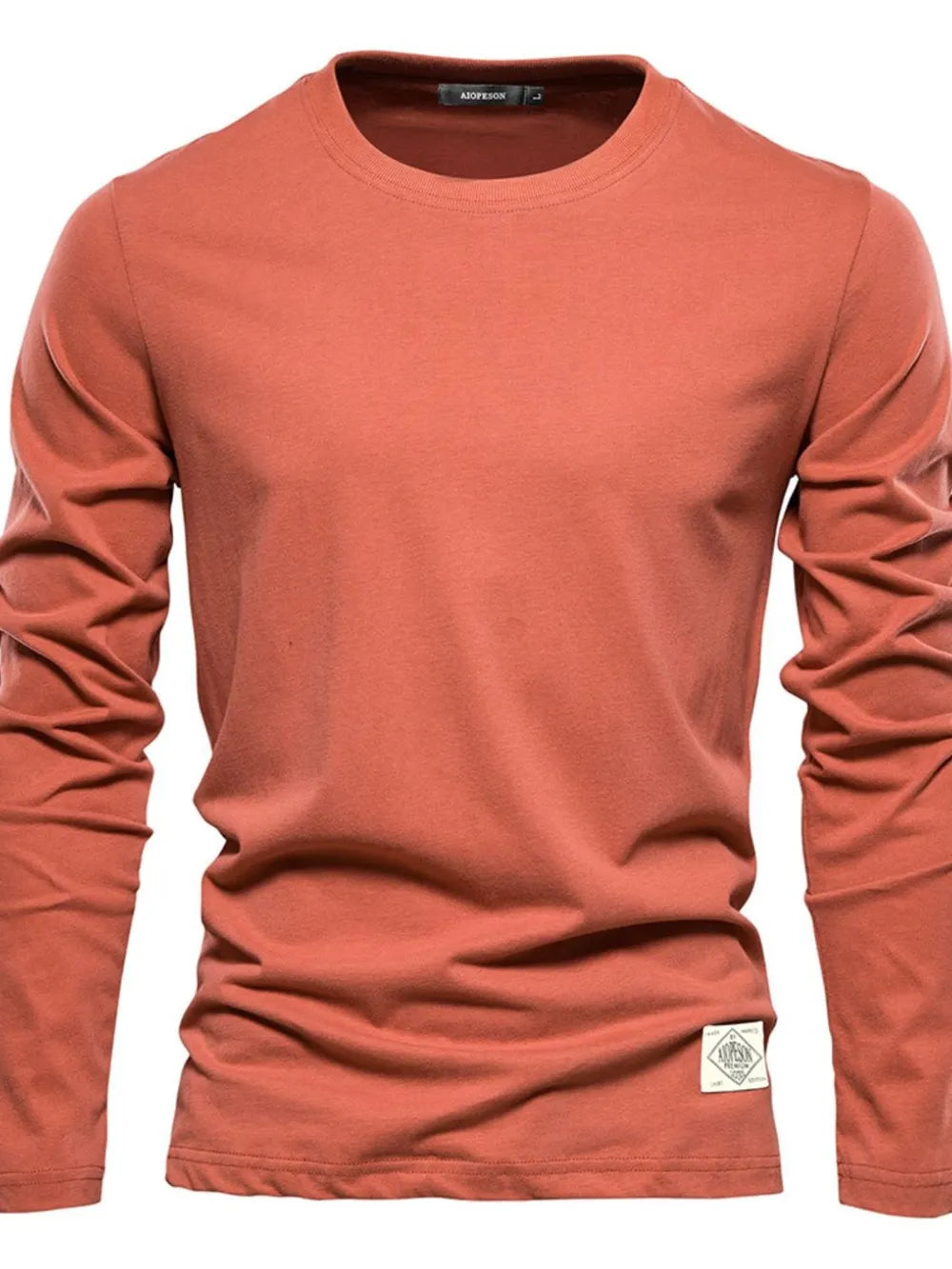 Coral crew-neck long sleeve tee with textured fabric and a logo patch detail.